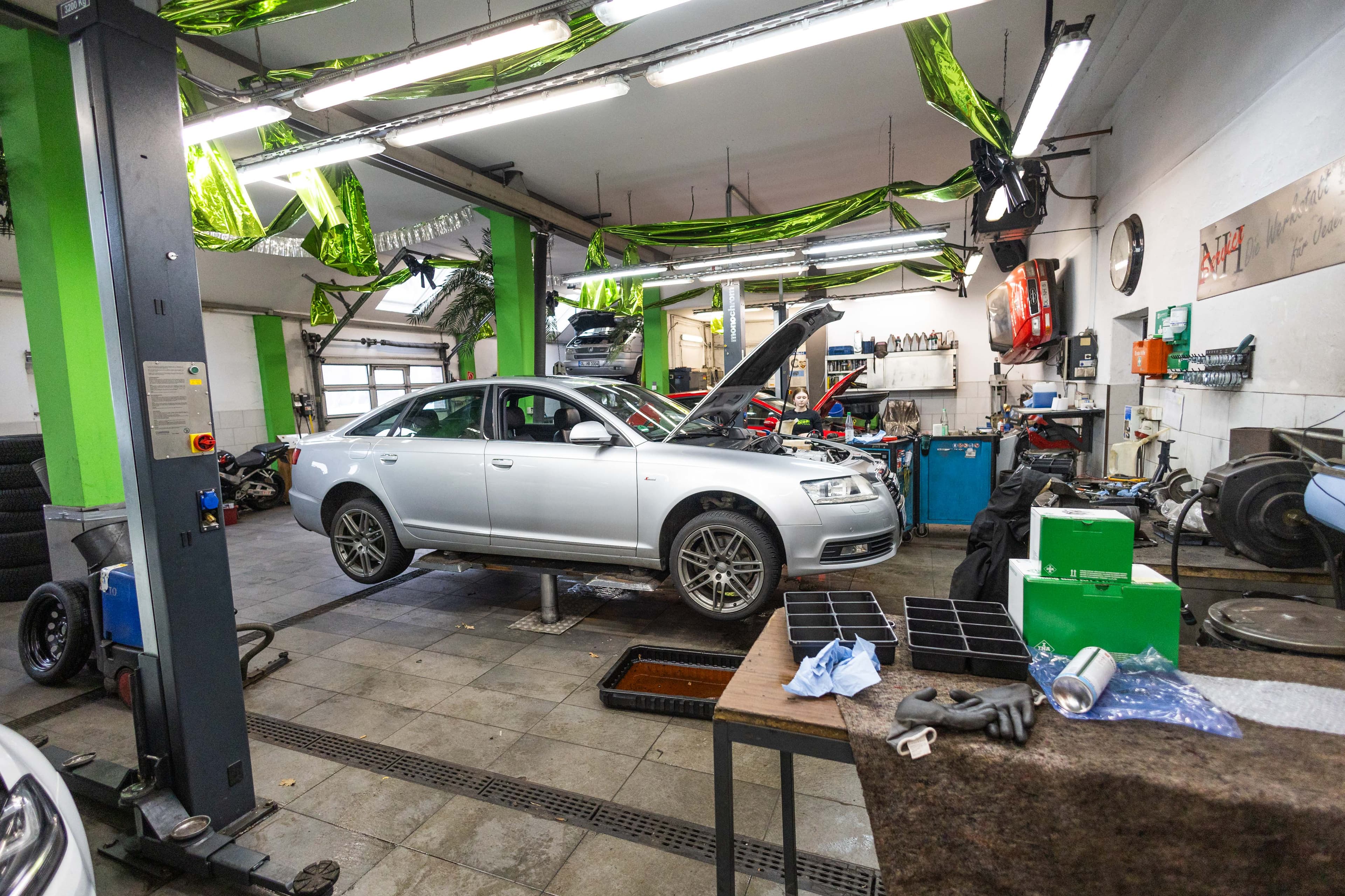 Werkstatt-Innenansicht mit silbernem Audi auf der Hebebühne