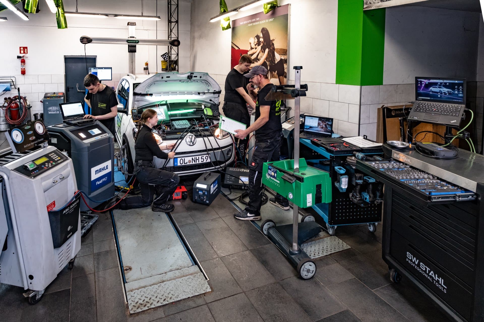 NH-Service Team bei Diagnose und Scheinwerfereinstellung an einem VW up in der Werkstatt Hude – mit Mahle-Klimaservicegerät und Getriebespülgerät